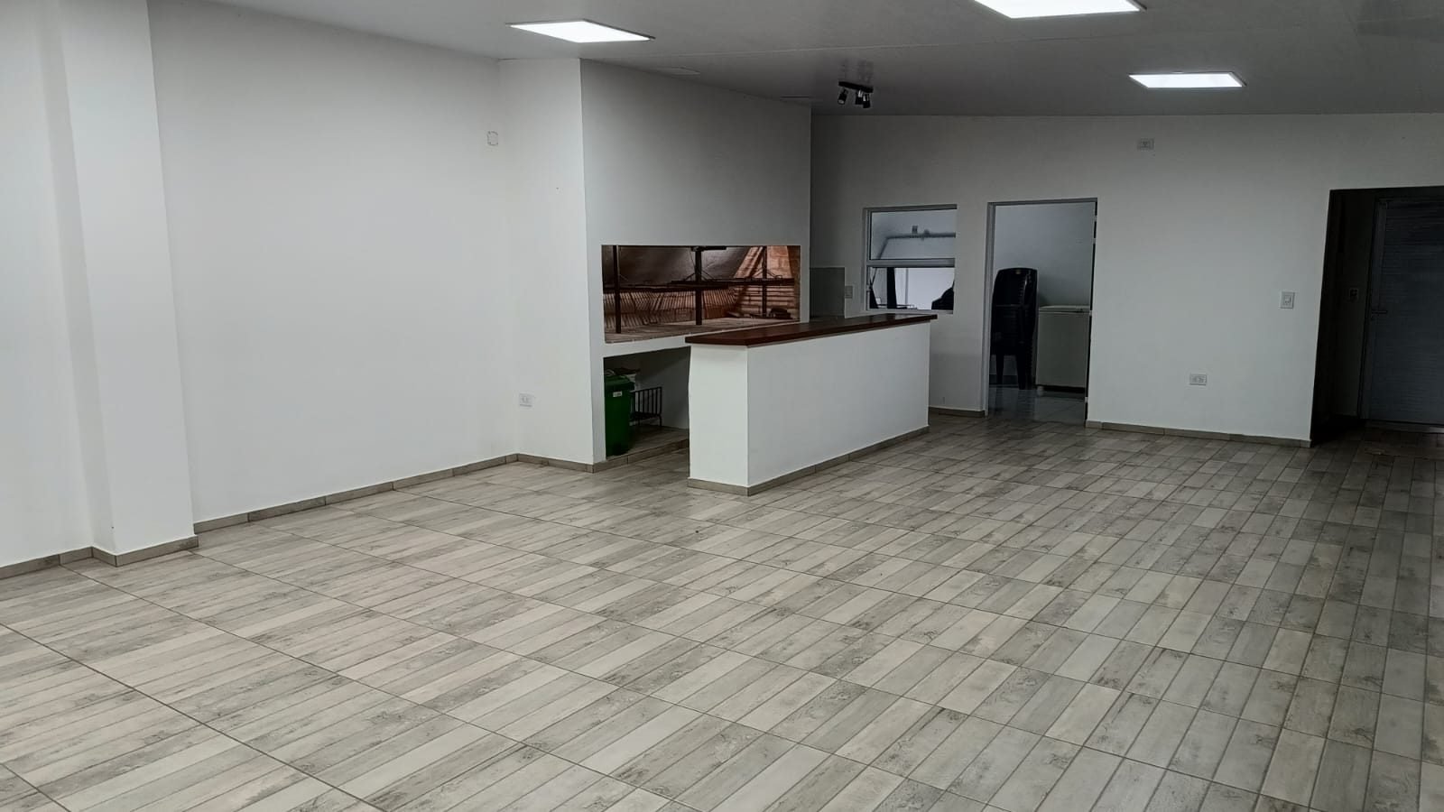 Salón amplio con piso símil madera y barra